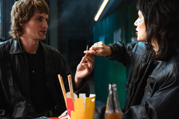 Caucasian man giving marijuana cigarette to his girlfriend while sitting at street cafe