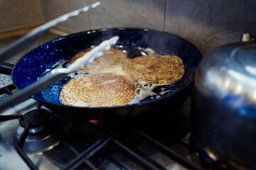 Drei Pfannkuchen werden in einer Bratpfanne zubereitet