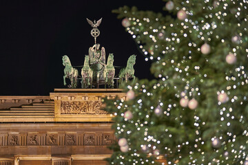 Germany Berlin, Christmas tree in front of illuminated Brandenburg Gate in Berlin City in the evening with dark sky , close up 