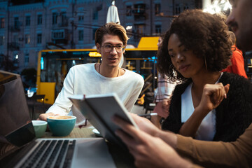 Multiracial woman working at night in the cafeteria with her friends