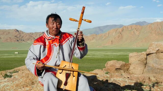 Mongolian throat singer performing old traditional folk song in the outdoors near the Altai Mountains, Bayan-Olgii Province, West Mongolia. 