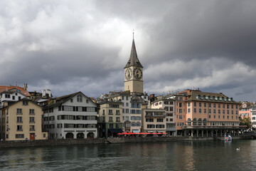 View of the promenade of Limmat river and ancient St. Peter Church. Zuerich, Switzerland, Europe.