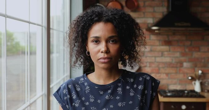 Head shot sad 30s African woman staring at camera, looks distressed due to divorce, breakup, suffer from anxiety or mental pain, experiences personal troubles, abuse vulnerable female portrait concept