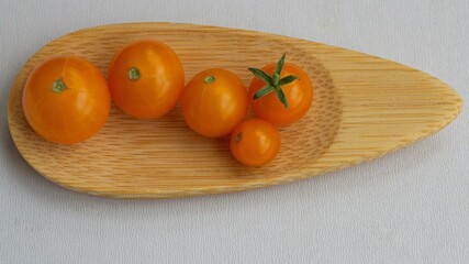 Very small tomatoes (orange cherry) on wooden spoon