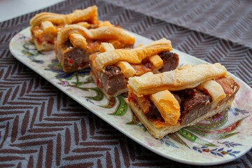 Homemade food. Pieces of fresh meat pie on a long plate in an asia style 