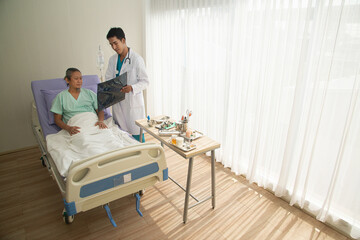 A Asian male doctor holds a brain X-ray film where CT scans the patient and analyzes the results...