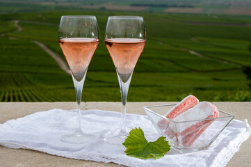Symbols of Reims, rose brut champagne wine and rose biscuits and view on green pinot noir grand cru vineyards of famous champagne houses in Montagne de Reims near Verzenay, Champagne, France