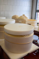 Process of making wheels of parmigiano-reggiano parmesan cheese on small cheese farm in Parma, Italy