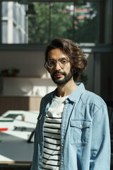 Portrait of young male professional computer app programmer designer of the IT department, standing in a modern office