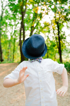 Portrait of a young boy playing with a hat over his face