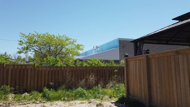 Maitenance Workers In Light White Clothing Power Washing Top Of New Bilding While Standing On Rooftop 