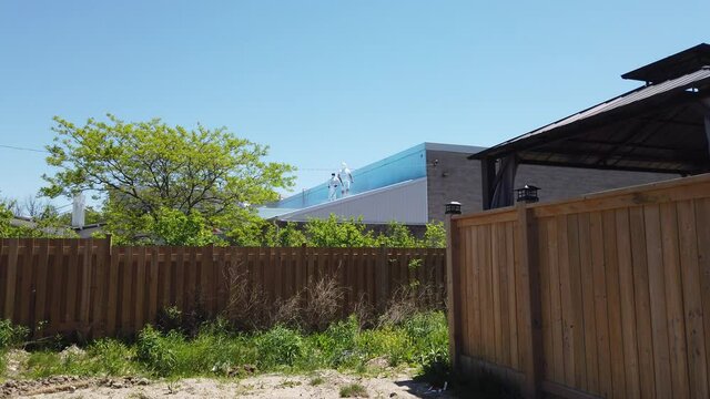Maitenance Workers In Light White Clothing Power Washing Top Of New Bilding While Standing On Rooftop 002
