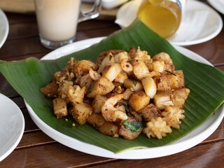 Singapore Black Carrot Cake with squid and prawns on banana leaf. Eating hawker food in a restaurant.