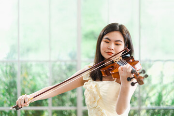 Asian women play the violin indoor. Portrait of a female violinist who is playing a string...
