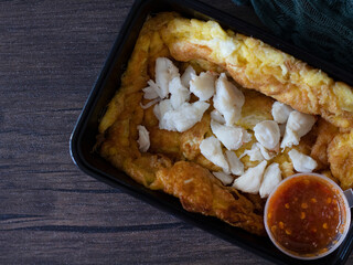 Thai Crab Omelette in a Takeaway Box. Bangkok Street Food shot on wooden table with copy space.