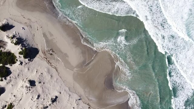 waves roll on the beach of rena majore in sardinia, bird's eye view with the drone