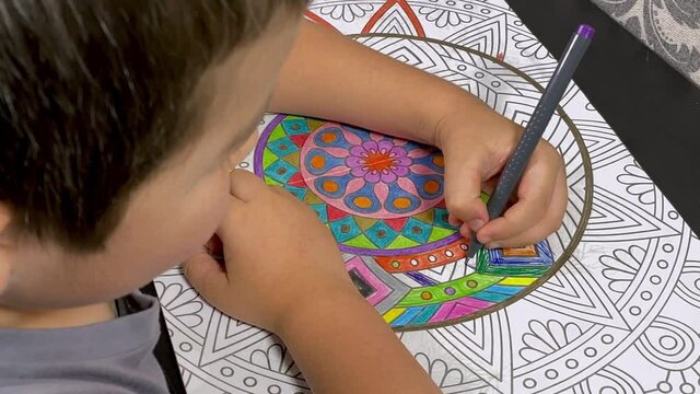 Ni&ntilde;o dibujando cuaderno de mandalas mano zurda
