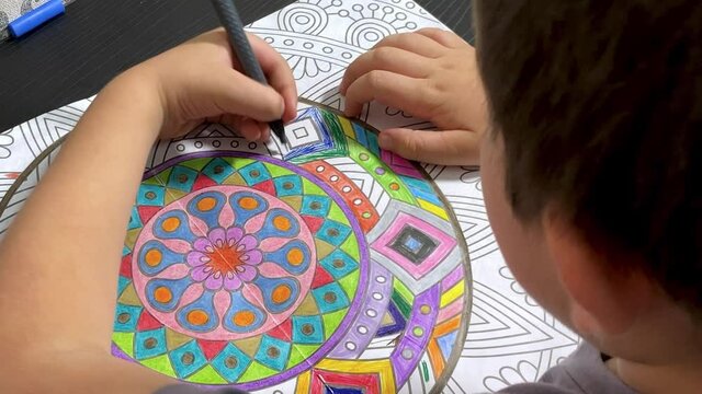 Ni&ntilde;o zurdo dibujando cuaderno de mandalas