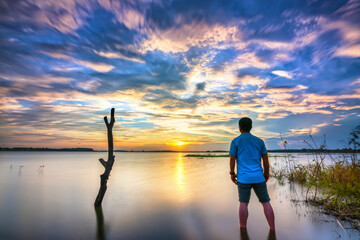 Silhouette traveler man watching the sunset at the hydroelectric lake as a way to relax after a...