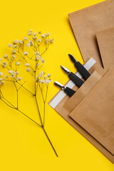 Paper bag with manicure equipment and flowers on yellow background
