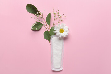 Menstrual pad and flowers on pink background