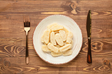 Plate with delicious dumplings and cutlery on wooden background