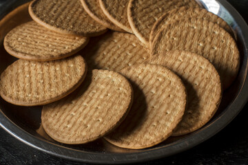 A steel plate full of English marie biscuits with dark background. Selective focus.