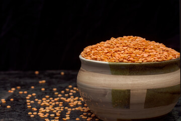 A bowl full of organic munsoor dal or lintel with dark background. Selective focus.