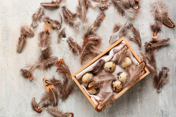 Wooden box with pheasant feathers and eggs on grunge background