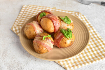 Plate of delicious baked potatoes with bacon on light background