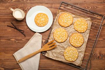 Grid with tasty chocolate cookies and jug of milk on wooden background