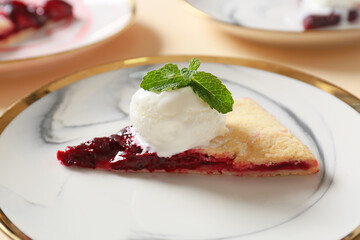 Plate with piece of fresh plum galette and ice cream on table, closeup