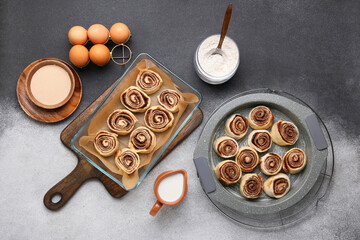 Baking dish of uncooked cinnamon rolls and ingredients on black and white background