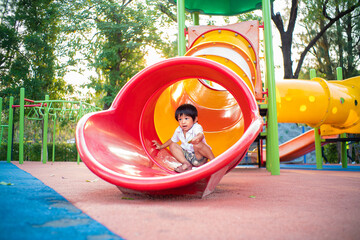 Preschoole little boy playing slider on playground in city park