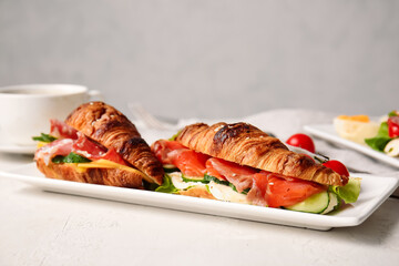 Plate with delicious croissant sandwiches on white background