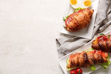 Plates with delicious croissant sandwiches on white background