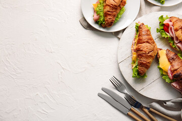 Wooden board and plate with delicious croissant sandwiches on white background - obrazy, fototapety, plakaty