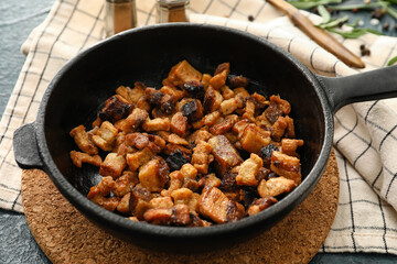 Fototapeta premium Frying pan with tasty cracklings on black background