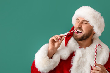 Santa Claus eating candy canes on green background