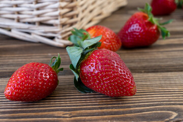 Strawberry in basket and on table on wooden background