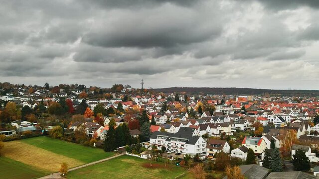 Aerial pullback, small town community on gloomy day in Dietzenbach, Germany. Dietzenback observation tower in distance