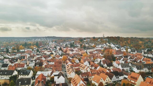 Aerial, residential houses with red roofs in German suburb on gloomy overcast day, cinematic 4K, epic dramatic clouds