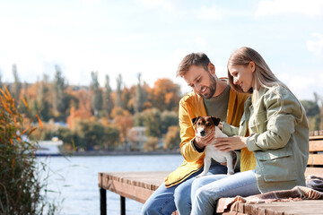 Lovely couple with cute Jack Russel terrier near river on autumn day