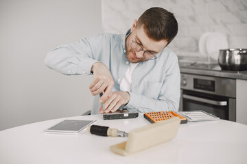 Fototapeta na wymiar Young disabled man repairing motherboard at kitchen
