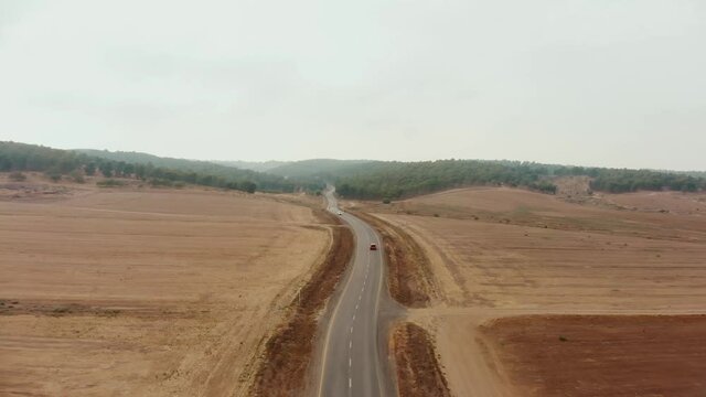 drone aerial shot of the desert's empty road showing the endless horizon and a far forest nirvana