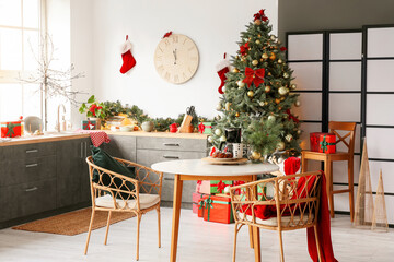 Interior of light modern kitchen with Christmas tree and dining table