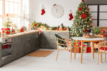 Interior of light modern kitchen with Christmas tree and dining table