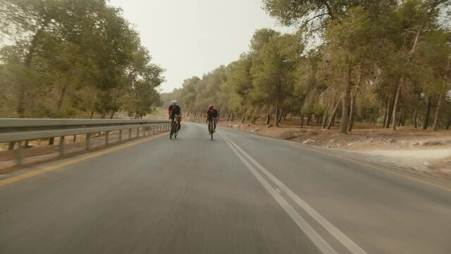 slow motion wide shot of two road cycelist professionals riding in the desert's empty road