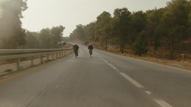 two road cycelist professionals riding in the desert's empty road trying to gain more speed