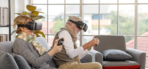 Naklejka premium Senior man and woman playing VR videogame